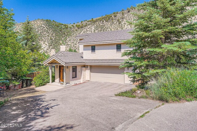 1140 June Creek Rd, Edwards, CO 81632 - view of front of home with stucco siding, a garage, a mountain view, asphalt driveway, and a chimney