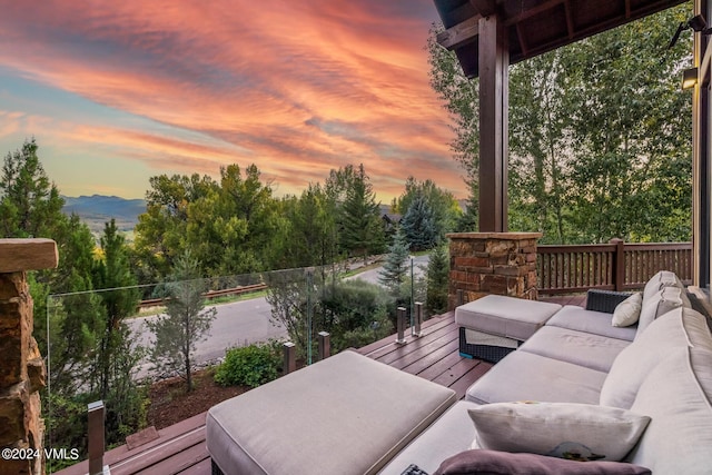 deck at dusk with an outdoor living space and a mountain view