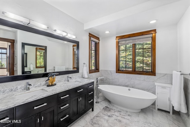 bathroom with vanity, a wealth of natural light, and a tub