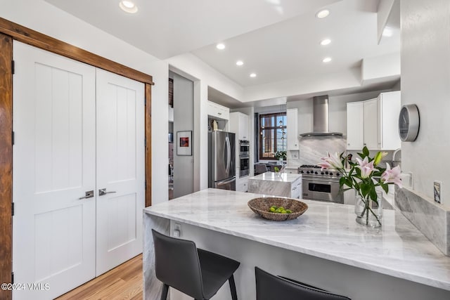 kitchen featuring white cabinetry, appliances with stainless steel finishes, and wall chimney range hood