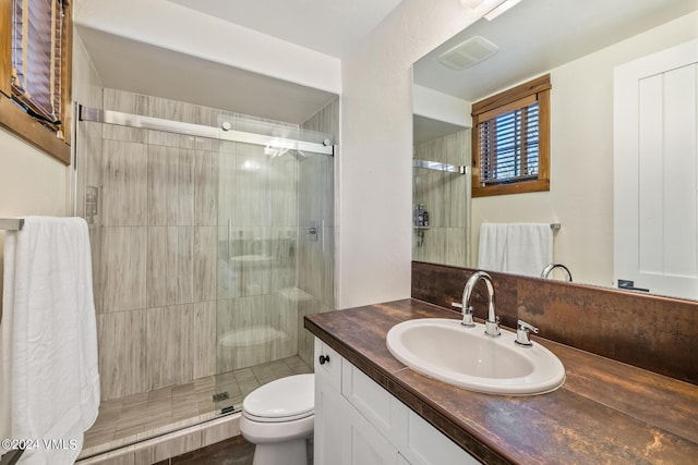 bathroom featuring vanity, a shower with door, and toilet