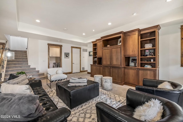 living room with a tray ceiling and light carpet