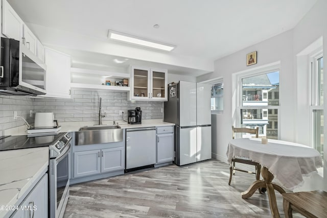 kitchen featuring sink, appliances with stainless steel finishes, light stone countertops, decorative backsplash, and white cabinets