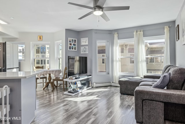 living room with ceiling fan, plenty of natural light, hardwood / wood-style floors, and baseboard heating