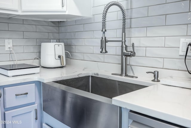 kitchen featuring sink, decorative backsplash, and white cabinets