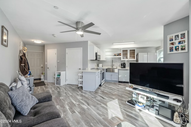 living room with sink, ceiling fan, and light hardwood / wood-style flooring