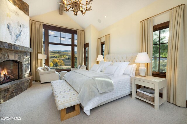 carpeted bedroom with a fireplace, vaulted ceiling, and a notable chandelier