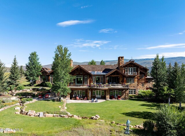 back of property featuring a patio, a mountain view, and a yard