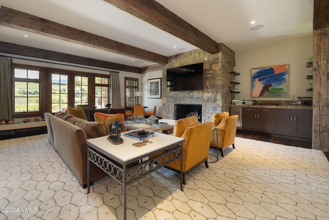 living room featuring beam ceiling and a stone fireplace