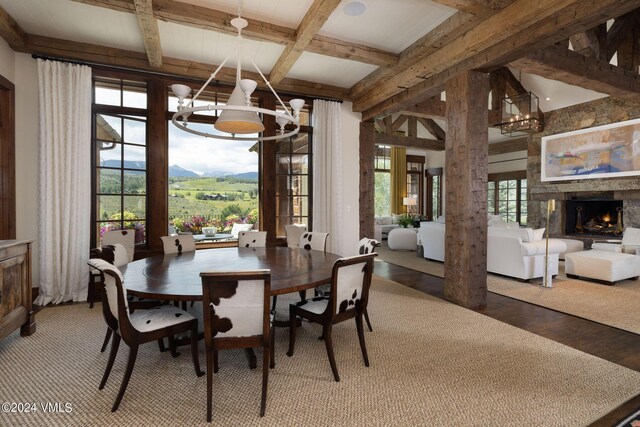 dining area featuring a notable chandelier, a stone fireplace, hardwood / wood-style floors, and a healthy amount of sunlight