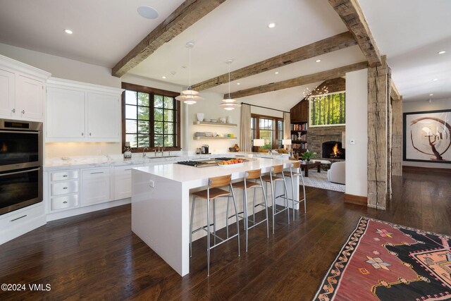 kitchen with pendant lighting, white cabinetry, a kitchen breakfast bar, a center island, and stainless steel double oven