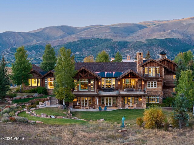 rear view of house featuring a mountain view, a lawn, and a patio area