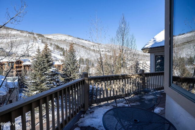 snow covered back of property featuring a mountain view