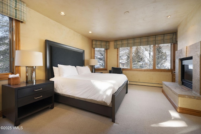 bedroom with a baseboard radiator, light carpet, a fireplace, and recessed lighting