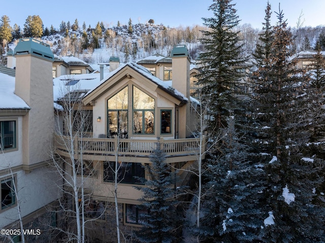 snow covered back of property with a chimney