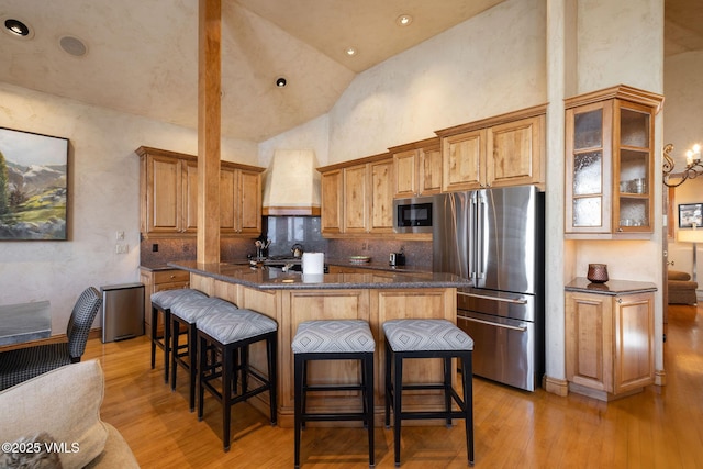 kitchen featuring light wood-style flooring, a kitchen breakfast bar, appliances with stainless steel finishes, a center island, and custom range hood