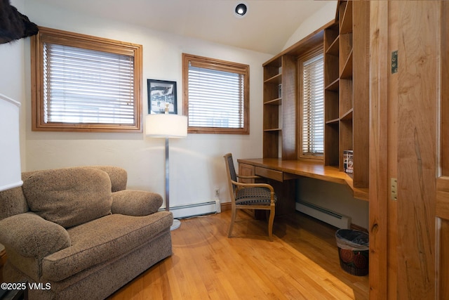 office area with lofted ceiling, light wood finished floors, baseboard heating, and built in desk