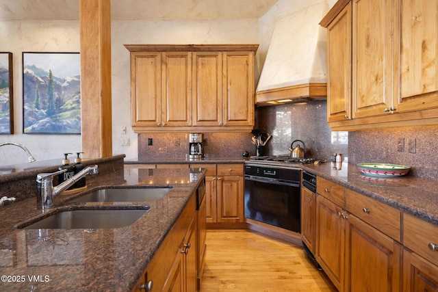 kitchen featuring stainless steel gas cooktop, custom exhaust hood, backsplash, a sink, and oven