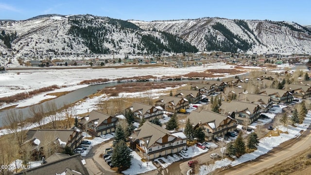 snowy aerial view with a mountain view and a residential view