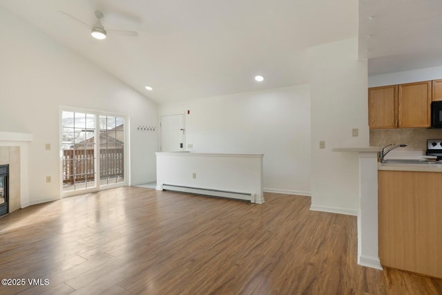 unfurnished living room with a baseboard heating unit, wood finished floors, recessed lighting, ceiling fan, and a tile fireplace