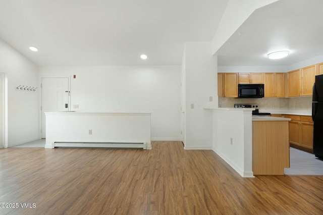 kitchen featuring a baseboard radiator, black appliances, light countertops, light wood-style floors, and tasteful backsplash