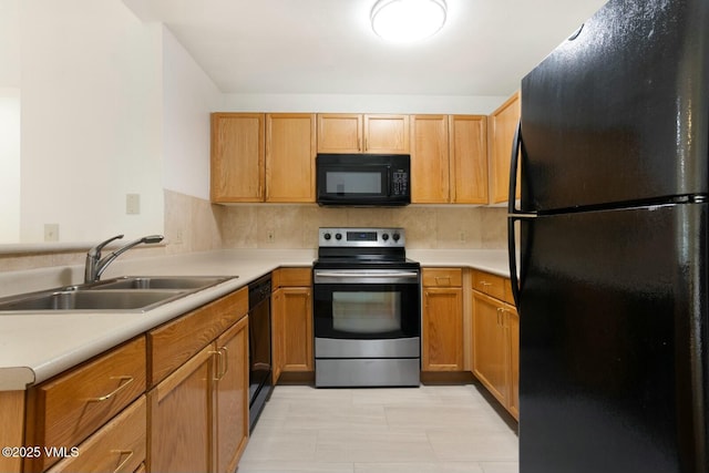 kitchen featuring a sink, tasteful backsplash, black appliances, and light countertops