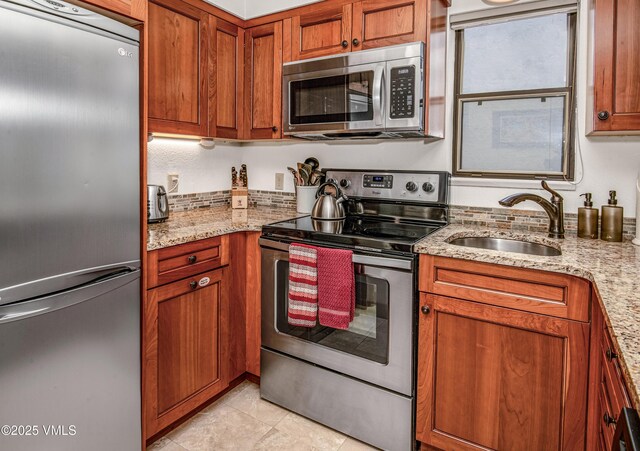 4610 Vail Racquet Club Dr Unit 7-12, Vail, CO 81657 - kitchen with appliances with stainless steel finishes, a sink, brown cabinetry, light stone counters, and light tile patterned flooring