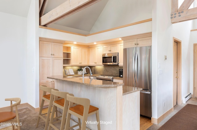 111 Scott Hill Rd Unit 17, Beaver Creek, CO 81620 - kitchen featuring appliances with stainless steel finishes, a baseboard radiator, decorative backsplash, light stone countertops, and a breakfast bar area