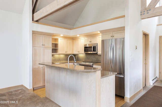 111 Scott Hill Rd Unit 17, Beaver Creek, CO 81620 - kitchen with stainless steel appliances, baseboard heating, decorative backsplash, light stone counters, and a kitchen island with sink