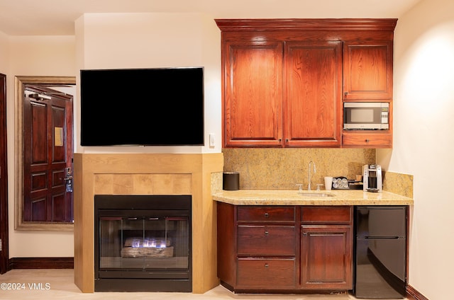 kitchen with fridge, sink, light stone counters, and backsplash