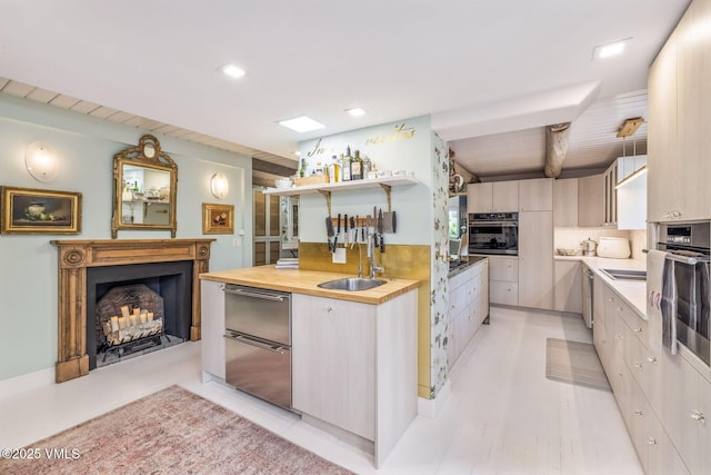 kitchen featuring beamed ceiling, butcher block counters, sink, and oven