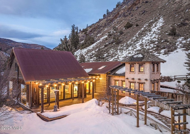 snow covered back of property featuring a mountain view