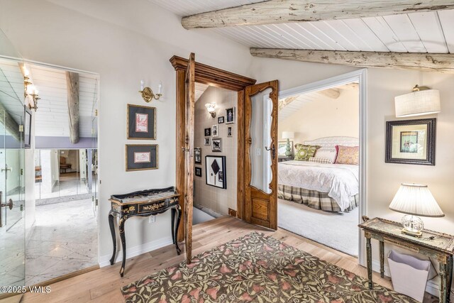 bedroom with light hardwood / wood-style flooring, lofted ceiling with beams, and wooden ceiling