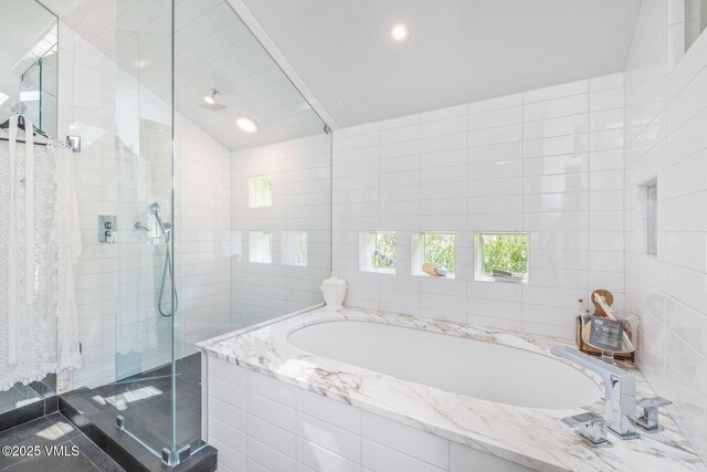 bathroom with tile walls, tile patterned flooring, lofted ceiling, and independent shower and bath