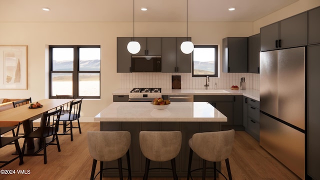 kitchen with tasteful backsplash, sink, hanging light fixtures, stainless steel appliances, and light wood-type flooring