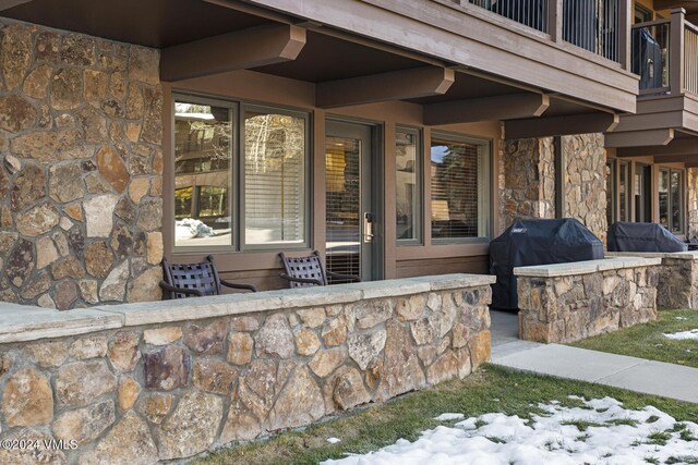 snow covered property entrance featuring a balcony