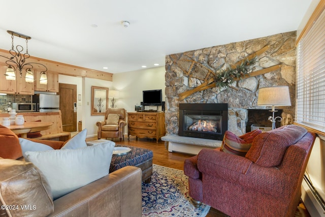 living room featuring a baseboard heating unit, a stone fireplace, wood finished floors, and recessed lighting