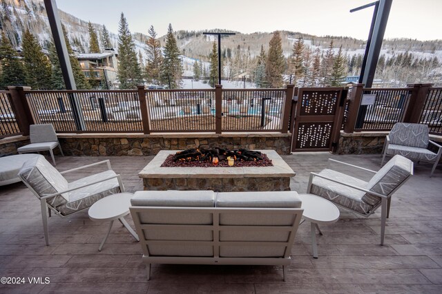 snow covered patio featuring a mountain view and a fire pit