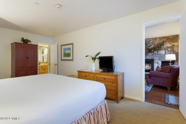 carpeted bedroom featuring a stone fireplace