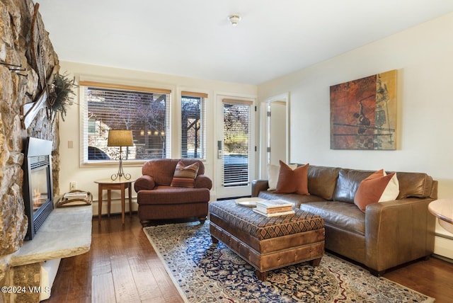 living room featuring a baseboard heating unit, dark wood-type flooring, and a fireplace