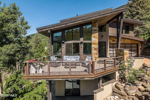 3235 Katsos Ranch Rd, Vail, CO 81657 - back of property featuring an attached garage, outdoor lounge area, stone siding, and a deck