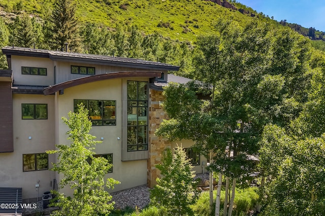 3235 Katsos Ranch Rd, Vail, CO 81657 - view of property exterior featuring stone siding, a forest view, and stucco siding