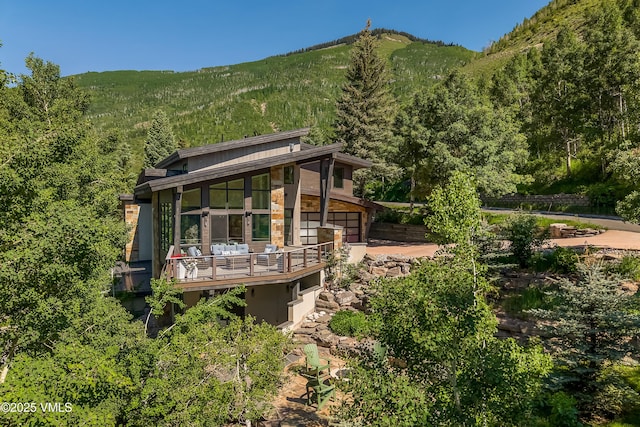 3235 Katsos Ranch Rd, Vail, CO 81657 - rear view of house with a view of trees, a mountain view, an attached garage, and stucco siding
