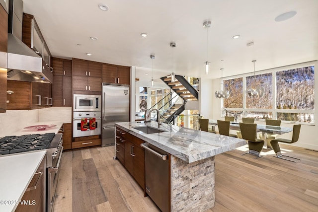 3235 Katsos Ranch Rd, Vail, CO 81657 - kitchen featuring built in appliances, wall chimney range hood, light wood finished floors, an island with sink, and recessed lighting