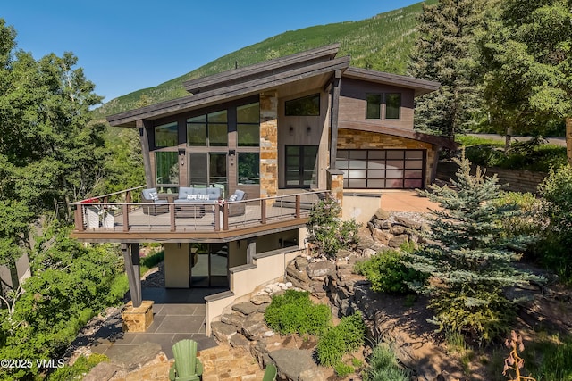 3235 Katsos Ranch Rd, Vail, CO 81657 - back of property with an attached garage, a deck with mountain view, and stone siding