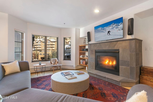 living room featuring a fireplace, wood-type flooring, and a baseboard heating unit