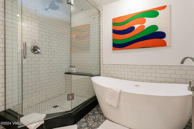 bathroom featuring tile walls and plus walk in shower