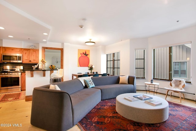 living room with light wood-type flooring, sink, and a baseboard radiator