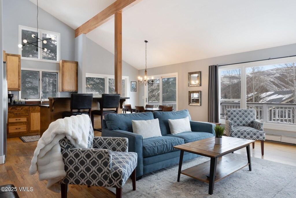 living room with an inviting chandelier, hardwood / wood-style flooring, beam ceiling, and high vaulted ceiling