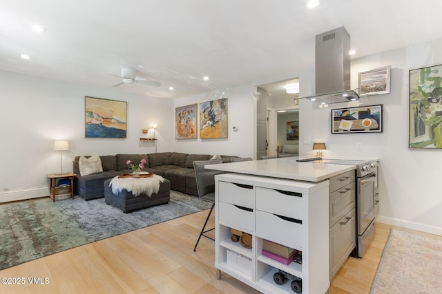2783 Kinnikinnick Rd Unit 7, Vail, CO 81657 - kitchen featuring stainless steel electric stove, island exhaust hood, light wood-type flooring, white cabinetry, and light countertops